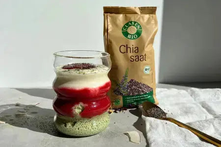 Geschichteter Strawberry‑Matcha‑Chiapudding im Glas mit grüner Matcha‑Chiaschicht, rotem Erdbeerpüree, heller Joghurtschicht und Chia als Topping.