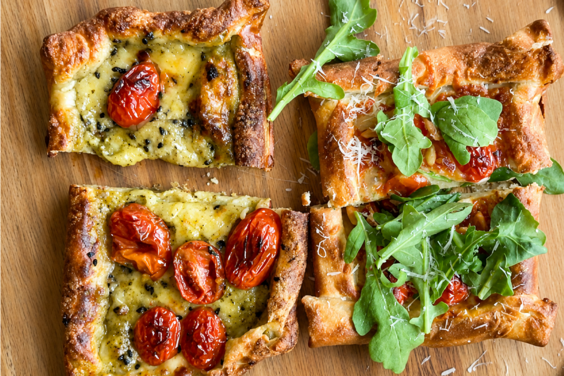Knusprige Reispapier-Pizzen mit geschmolzenem Käse und gerösteten Cherrytomaten auf einem Holzbrett. Einige Stücke sind zusätzlich mit frischem Rucola und fein geriebenem Hartkäse belegt. Aufnahme von oben bei natürlichem Licht.