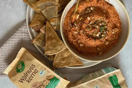 Muhammara in einer Schüssel, dekoriert mit gerösteten Walnüssen und einem Schuss Olivenöl, serviert als cremiger Walnuss‑Paprika‑Dip.