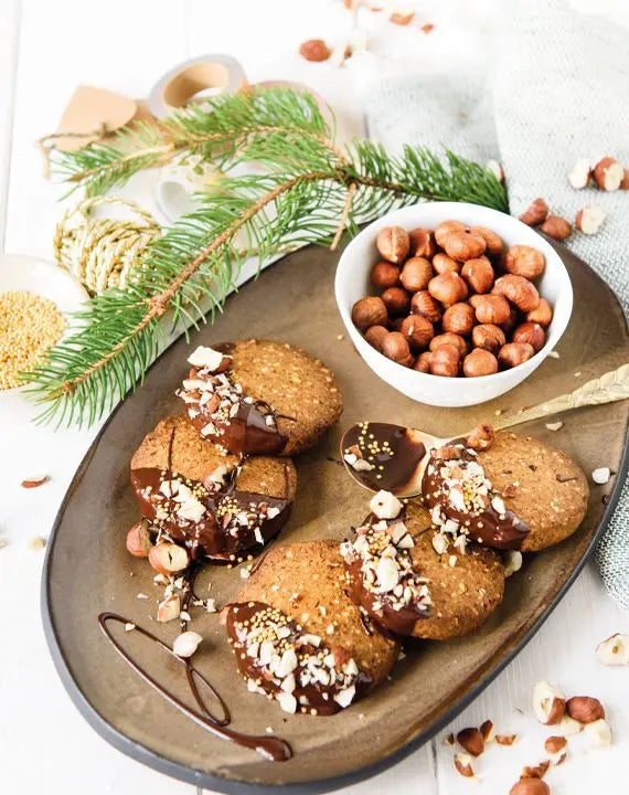Amerikanische Haselnuss-Walnuss-Cookies mit Ahornsirup auf einem Keramikteller, dekoriert mit Nüssen, Schokolade und Kokoschips