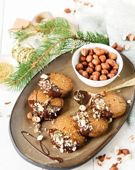 Amerikanische Haselnuss-Walnuss-Cookies mit Ahornsirup auf einem Keramikteller, dekoriert mit Nüssen, Schokolade und Kokoschips