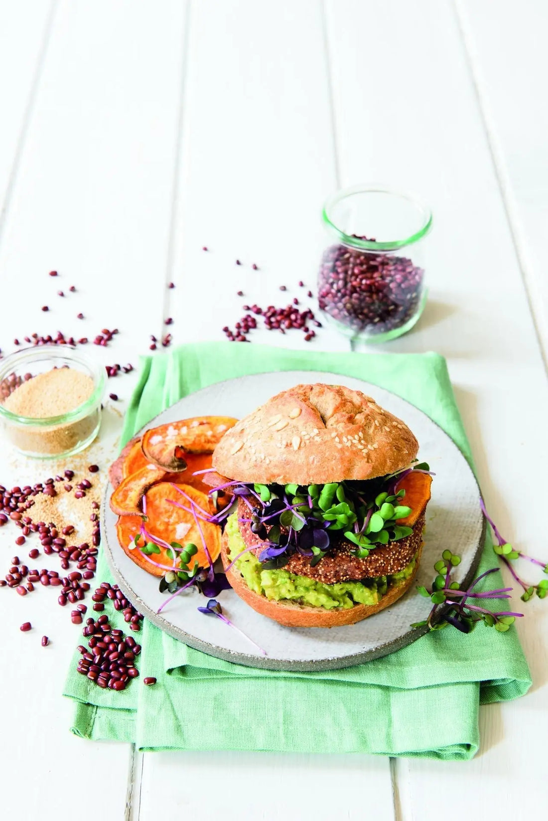Azukibohnen-Burger mit Avocado und frischer Kresse, serviert im Burgerbrötchen auf einem Teller