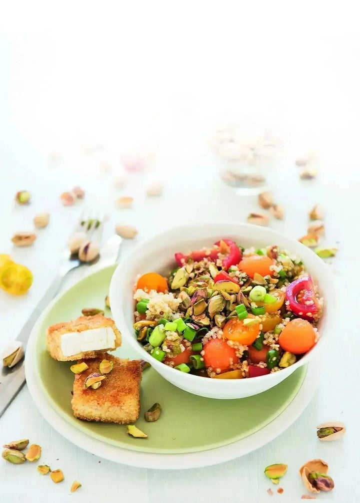 Bunter Quinoa-Salat mit Melonenstücken, Pistazien und knusprig paniertem Feta, frisch angerichtet auf einem Teller