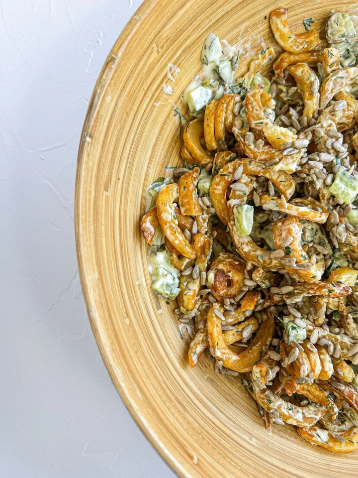 Curly-Fries Salat mit Sonnenblumenkernen, serviert auf einem Teller mit knusprigen Pommes