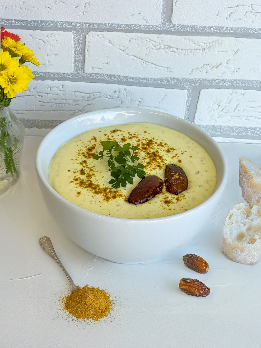Dattel-Curry-Dip in einer weißen Schale, garniert mit Currypulver, Datteln und frischer Petersilie