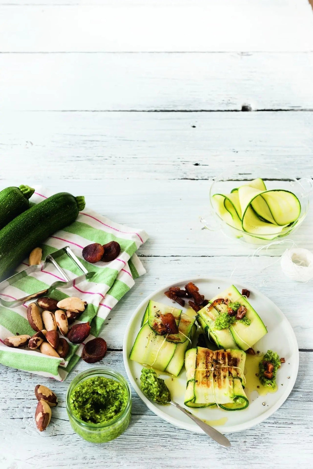 Feta-Zucchini-Päckchen mit Aprikosen und Paranuss-Pesto, dekorativ angerichtet auf einem weißen Teller mit sichtbaren Aprikosenstücken und grünem Pesto