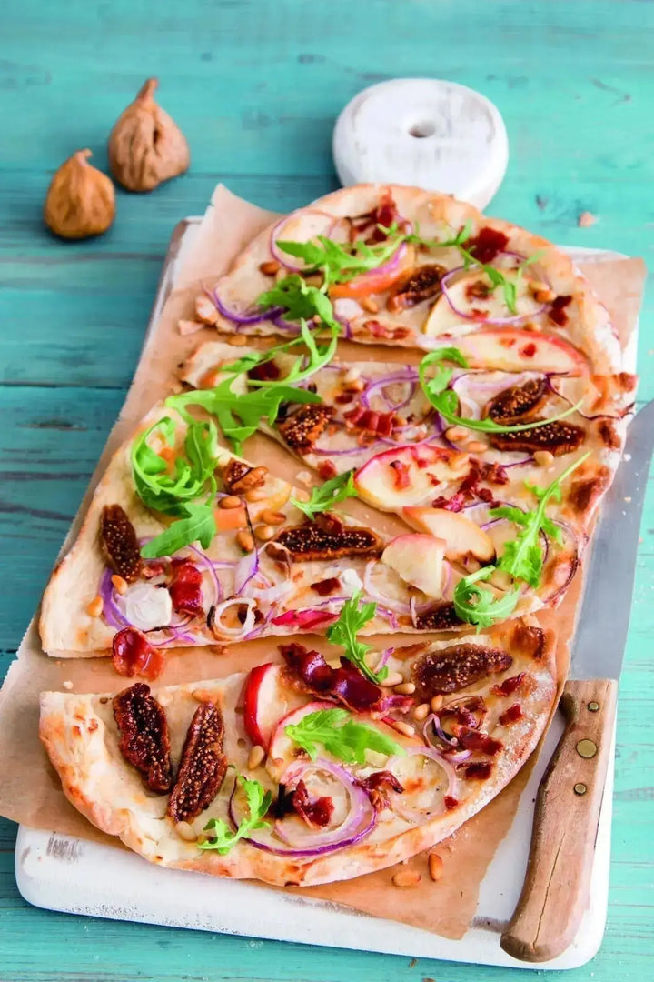 Flammkuchen mit frischen Feigen, Ziegenfrischkäse und knusprigen Baconchips, goldbraun gebacken und angerichtet auf einem Holzbrett