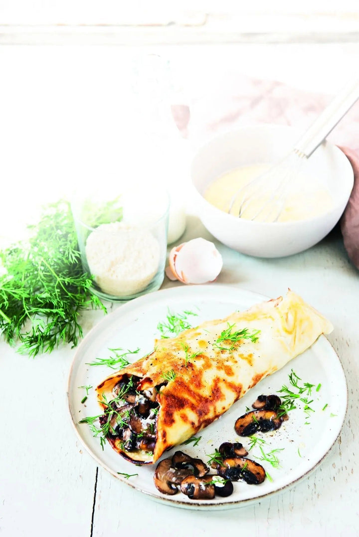 Gefüllte Mandelmehl-Pfannkuchen, aufgerollt und angerichtet auf einem Teller, mit sichtbarer Füllung