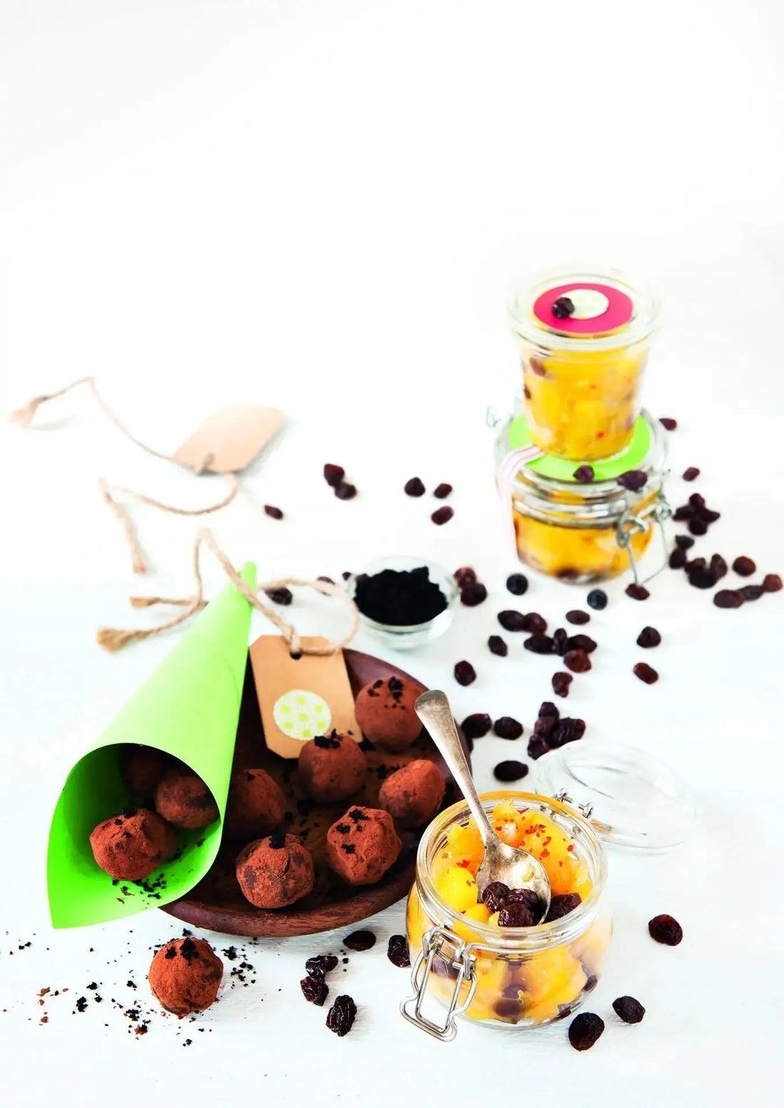 Schokoladen-Trüffel mit Açaipulver, daneben Gläser mit Ingwer-Mango-Chutney und Açaipüree, dekorativ angerichtet