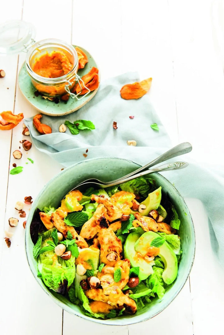 Knackiger Mango-Hähnchen-Salat mit Haselnusskernen, bunt angerichtet auf einem Teller mit frischen Salatblättern