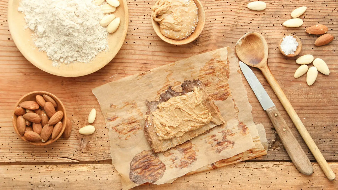 Lisas Mandelaufstrich auf dünnem Brot, serviert auf einem Holzbrett, mit Mandeln und etwas Salz als Dekoration