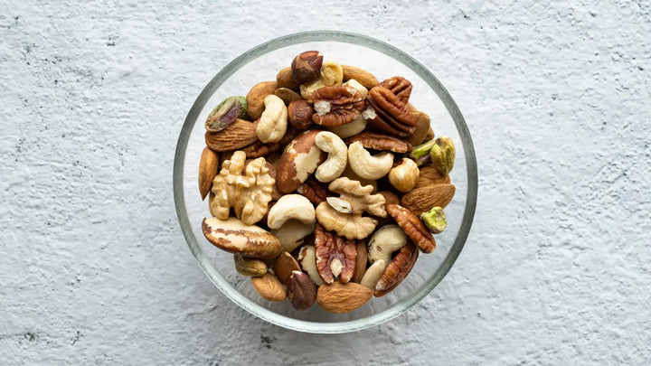 Von oben fotografierte Glasschüssel mit einer Mischung aus verschiedenen Nüssen wie Mandeln, Cashews, Walnüssen und Pistazien.