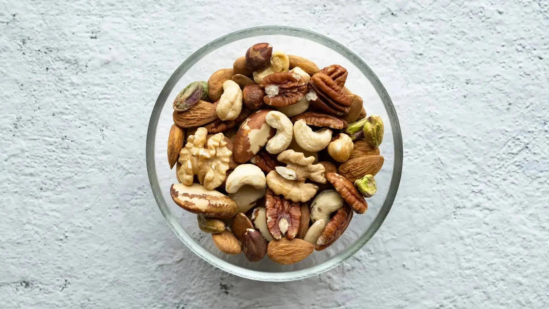 Von oben fotografierte Glasschüssel mit einer Mischung aus verschiedenen Nüssen wie Mandeln, Cashews, Walnüssen und Pistazien.