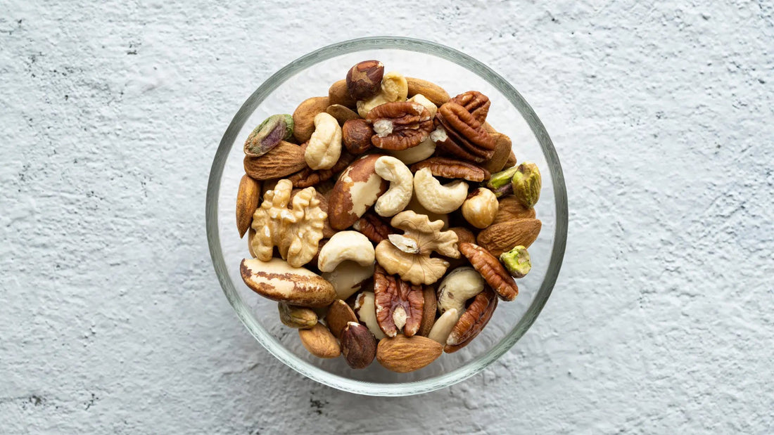 Von oben fotografierte Glasschüssel mit einer Mischung aus verschiedenen Nüssen wie Mandeln, Cashews, Walnüssen und Pistazien.