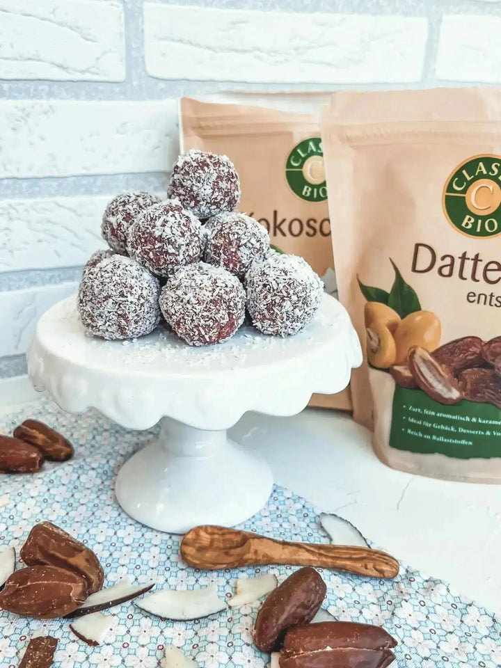 Pinke Energy Balls mit Datteln und Himbeeren, dekoriert mit Datteln und Kokoschips