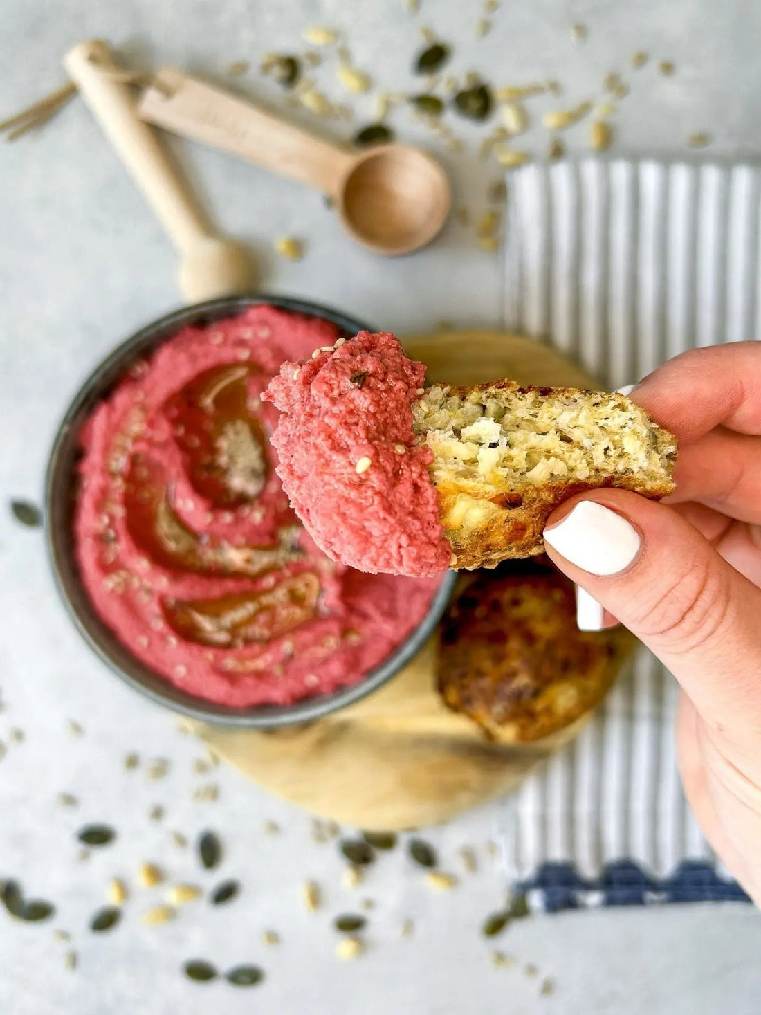 Pinkes Hummus mit roter Beete in einer Schale, serviert mit Ricotta-Bällchen und einer Auswahl an Samen als Beilage