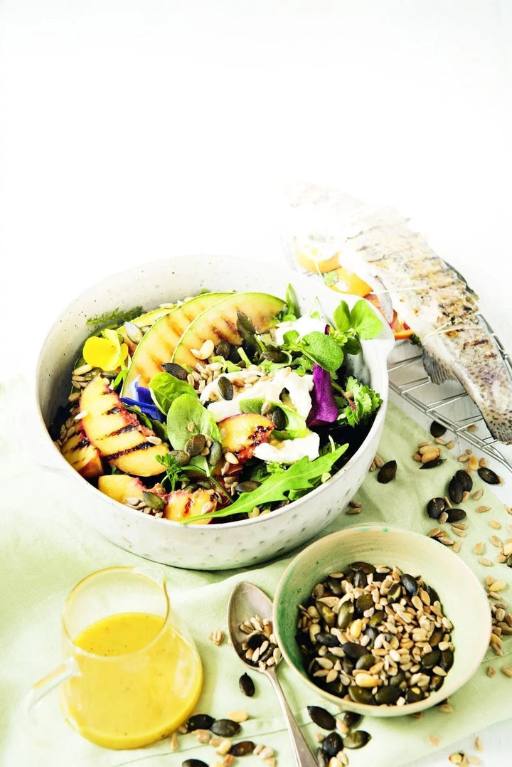 Sommersalat mit knusprigen Salatkernen und gegrillter Regenbogenforelle, frisch angerichtet auf einem Teller mit buntem Gemüse