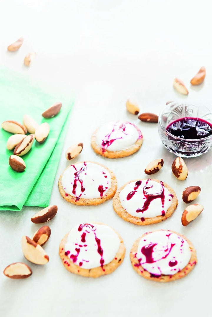 Splatter Cookies – Paranuss-Kekse mit dekorativem Himbeer-Blut, direkt auf dem Tisch serviert, mit sichtbaren Nussstücken und roter Fruchtsauce