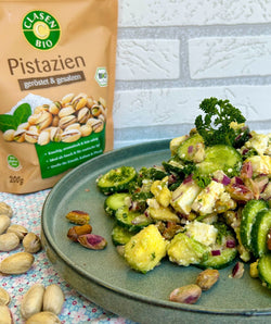 Chili-Lime-Gurkensalat mit gehackten Pistazien und frischer Petersilie auf einem Teller angerichtet.